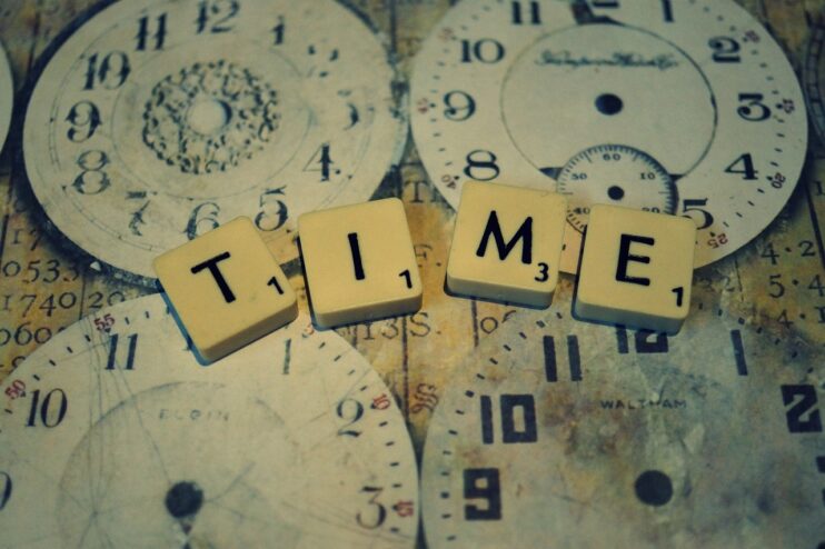 Vier oude klokken en de tekst TIME in scrabble-blokken