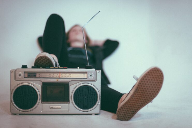 Jongen ligt met voet op ouderwetse radio met geknakte antenne