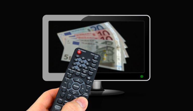 Hand richt afstandsbediening op een televisie met bankbiljetten in beeld