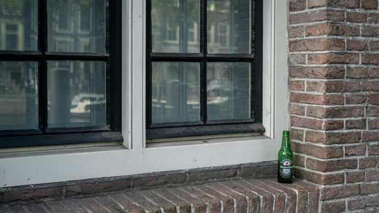 Flesje bier van Heineken staat allenig voor een Amsterdams raam
