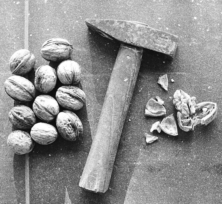 Notenallergie in de horeca, een stapel walnoten met een hamer ernaast die de walnoten kraakt