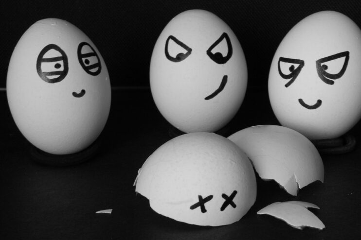 Drie eieren kijken boos naar een vierde kapotte eierschaal