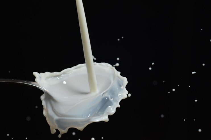 Een lepel waarop melk wordt gegoten die eraf spettert