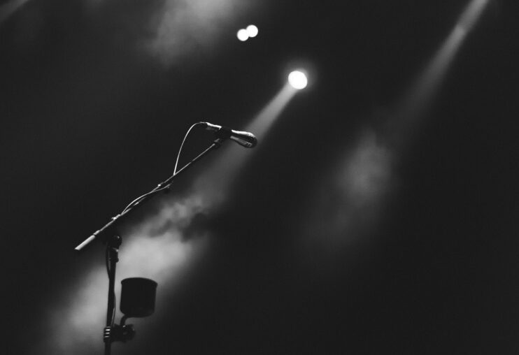 Een zwart-wit-foto van een microfoonstandaard en lichten, maar zonder zanger