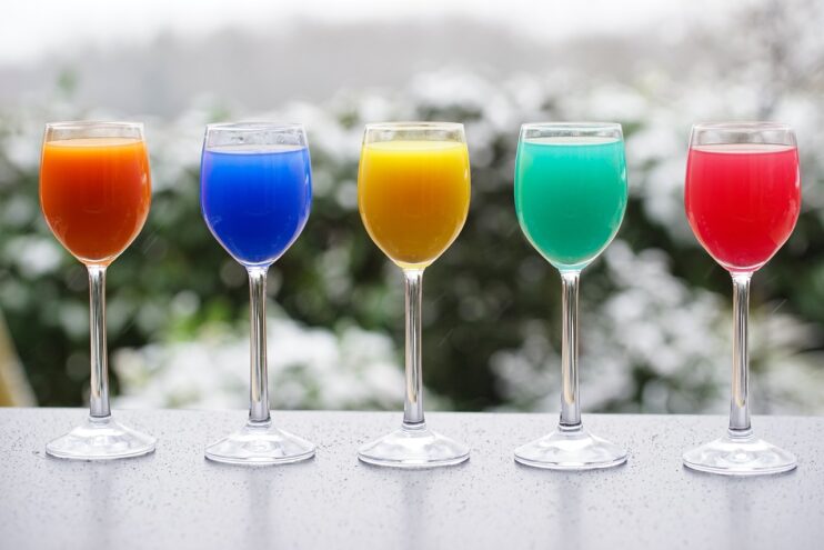 Vijf verschillende kleuren felgekleurde drank in een wijnglas