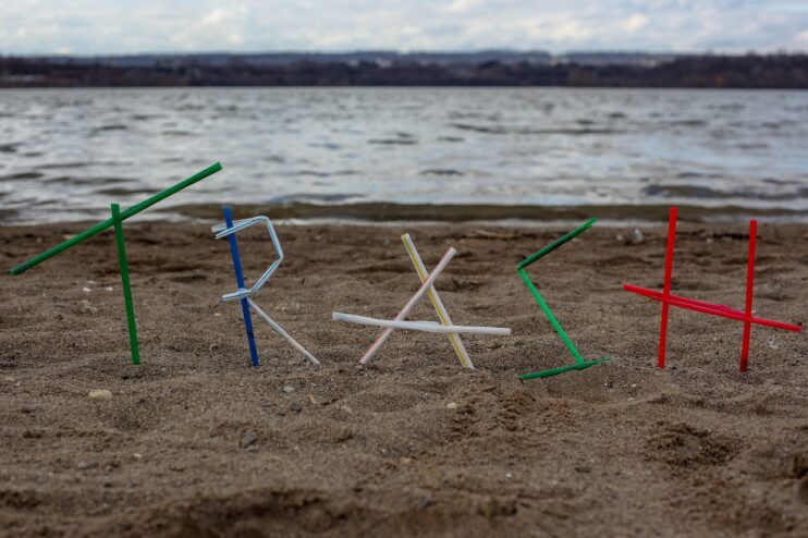 Plastic rietjes in de vorm van het woord TRASH op een strand